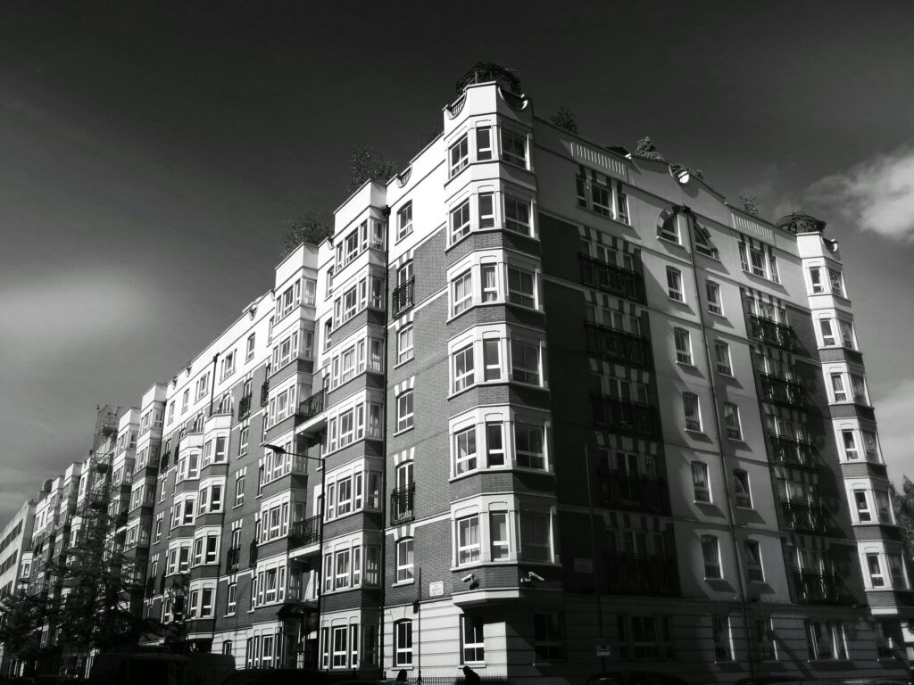 Black and white photo of a classic urban apartment building facade with windows.